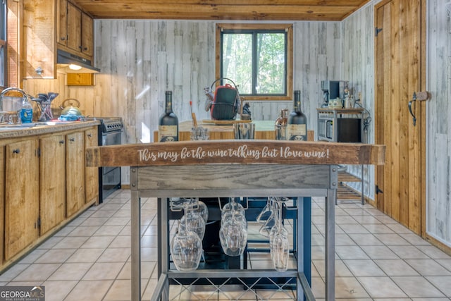 kitchen featuring electric stove, wooden walls, sink, and light tile patterned floors