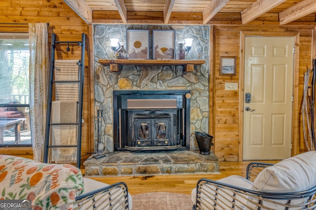 living room featuring wooden walls, beam ceiling, wooden ceiling, hardwood / wood-style floors, and a wood stove