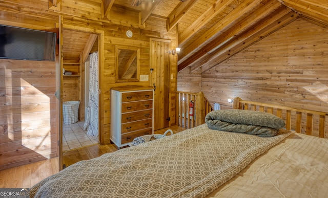 bedroom with lofted ceiling with beams, light hardwood / wood-style flooring, and wooden walls