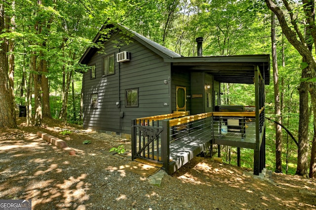 view of front of house featuring a wall unit AC and a wooden deck