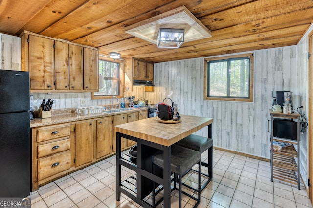 kitchen featuring black fridge, sink, wooden ceiling, and wood walls