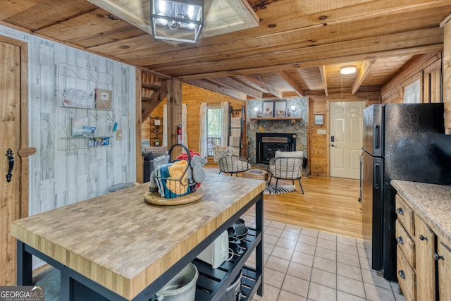 dining area featuring beam ceiling, wood walls, a fireplace, light tile patterned floors, and wood ceiling