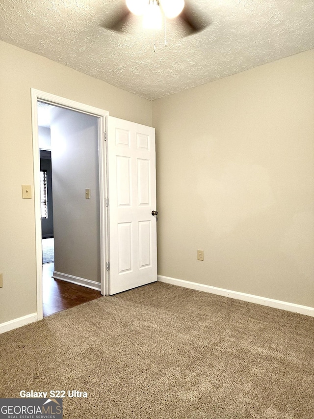 carpeted empty room featuring ceiling fan and a textured ceiling