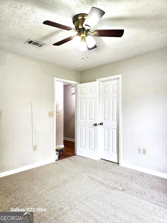 unfurnished bedroom with carpet flooring, a textured ceiling, and ceiling fan