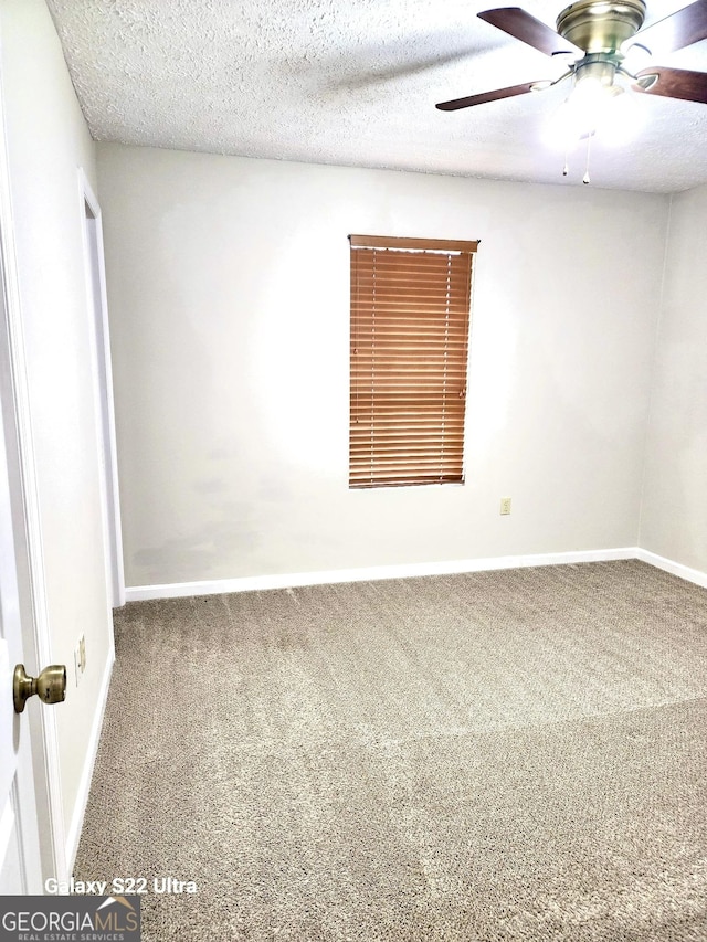 carpeted spare room featuring a textured ceiling and ceiling fan