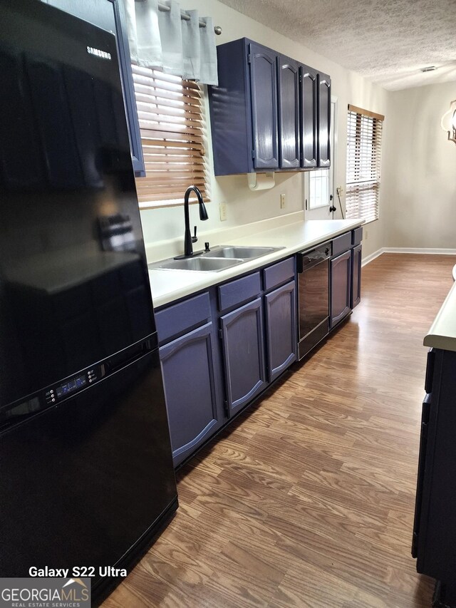 kitchen featuring blue cabinetry, sink, black appliances, and hardwood / wood-style flooring