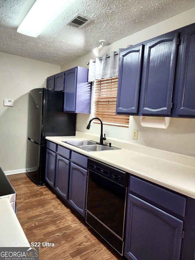 kitchen featuring dark wood-type flooring, black appliances, sink, a textured ceiling, and blue cabinetry