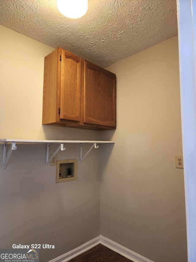 washroom with dark hardwood / wood-style flooring, cabinets, a textured ceiling, and hookup for a washing machine