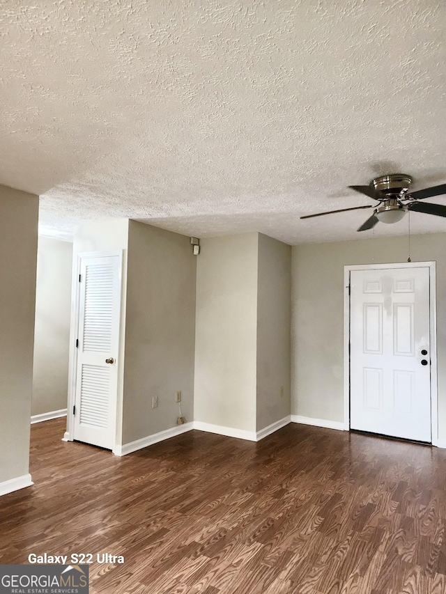 spare room featuring a textured ceiling, ceiling fan, and dark wood-type flooring