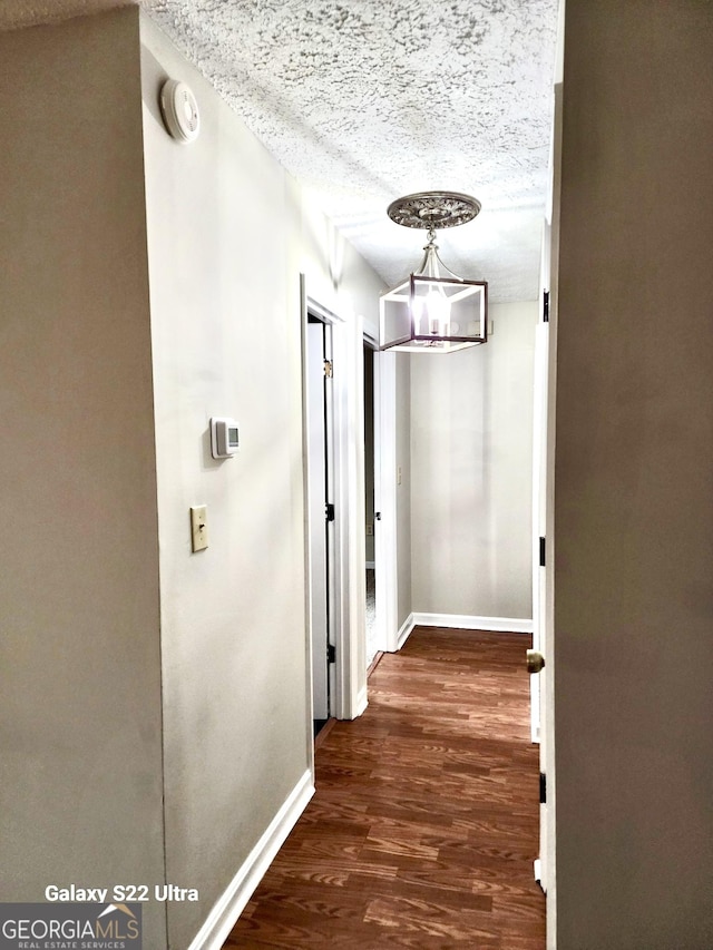 hall with dark hardwood / wood-style flooring and a textured ceiling