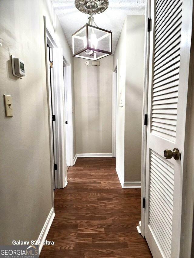 hallway featuring a chandelier, a textured ceiling, and dark hardwood / wood-style floors