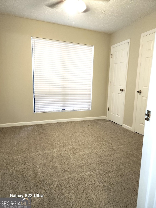 carpeted empty room with ceiling fan and a textured ceiling