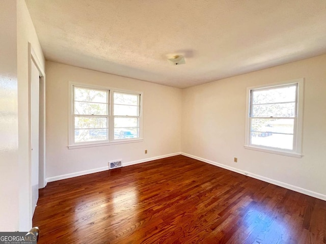 unfurnished room featuring dark hardwood / wood-style flooring and a textured ceiling