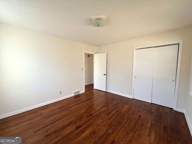 unfurnished bedroom featuring dark hardwood / wood-style flooring and a closet