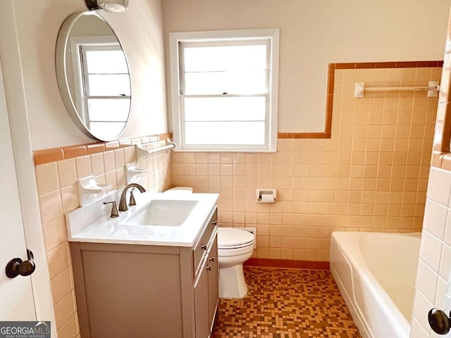 bathroom with vanity, toilet, tile walls, and a bathing tub