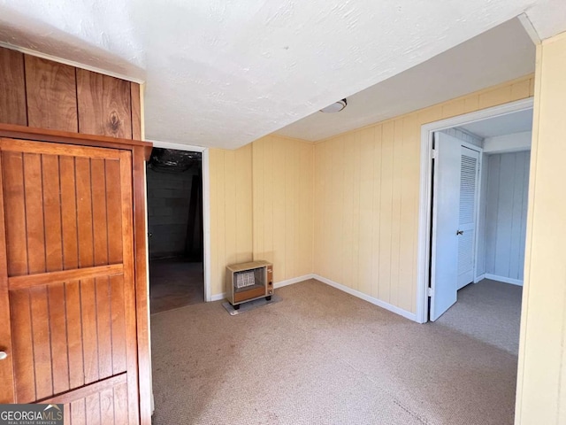 empty room featuring carpet floors, heating unit, and wooden walls