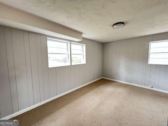 carpeted spare room featuring wood walls