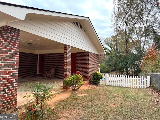 view of property exterior with a carport, brick siding, and fence