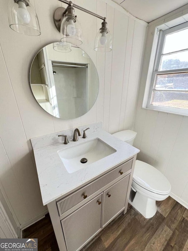 bathroom with wood walls, vanity, wood-type flooring, and toilet