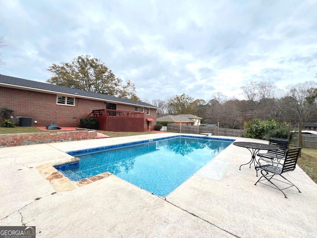 view of pool featuring a wooden deck, a patio, and central AC unit