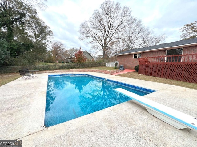 view of pool featuring a diving board, a patio area, and a wooden deck