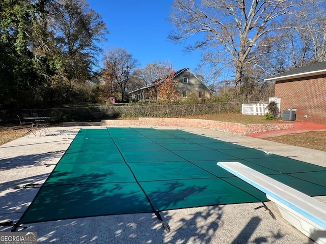 view of pool with a diving board, a patio area, and central air condition unit