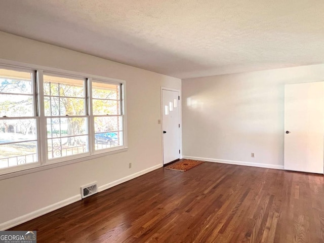 empty room featuring dark hardwood / wood-style floors and a textured ceiling