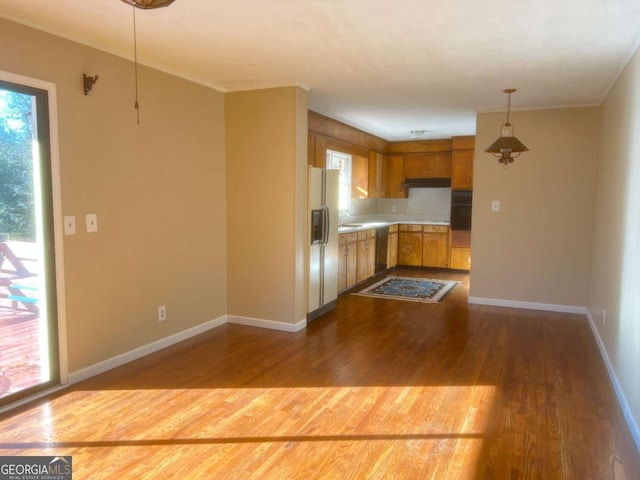 kitchen with dishwashing machine, sink, white refrigerator with ice dispenser, wood-type flooring, and decorative light fixtures