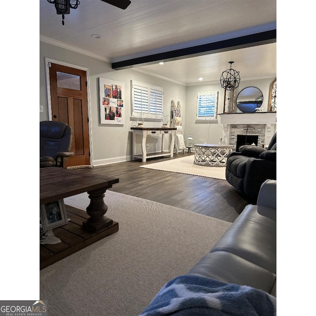 living room featuring a stone fireplace, wood-type flooring, ornamental molding, beamed ceiling, and ceiling fan