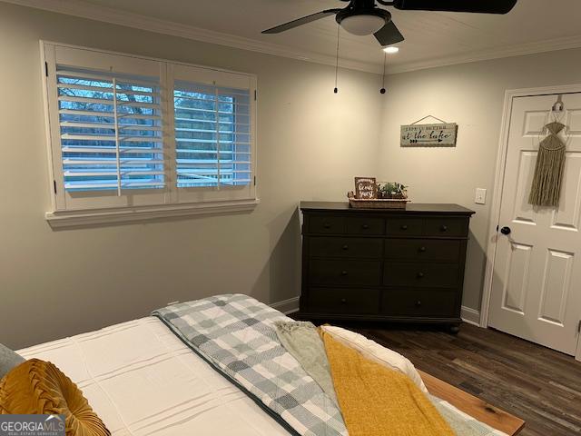 bedroom with dark hardwood / wood-style flooring, ornamental molding, and ceiling fan