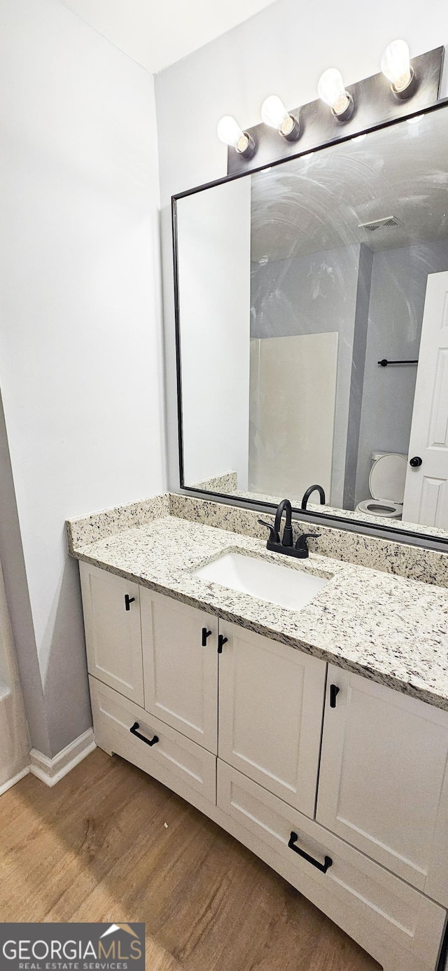 bathroom with hardwood / wood-style flooring, vanity, and toilet