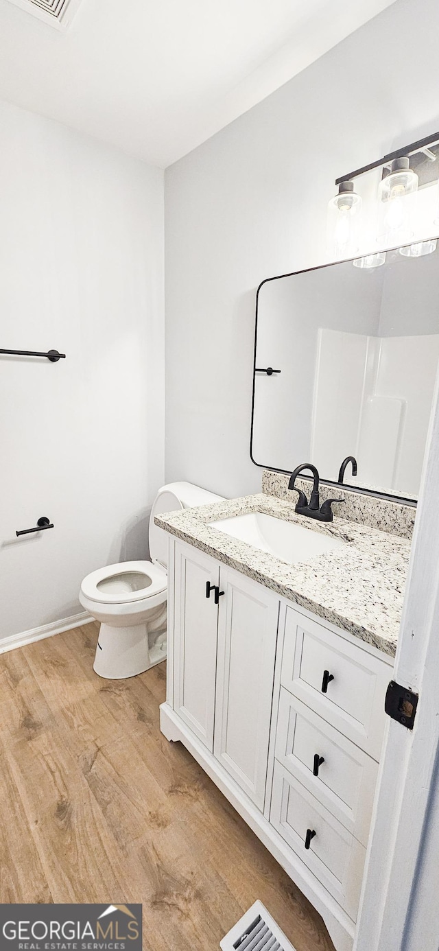 bathroom with hardwood / wood-style flooring, vanity, and toilet