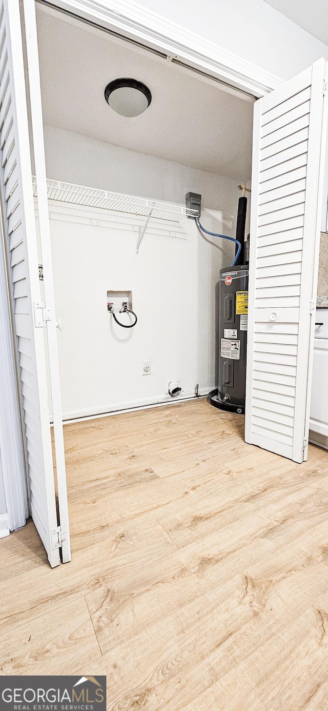 laundry room with electric water heater and light wood-type flooring