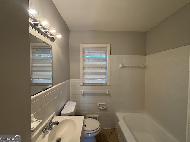 bathroom featuring tile walls, a bathtub, sink, and toilet