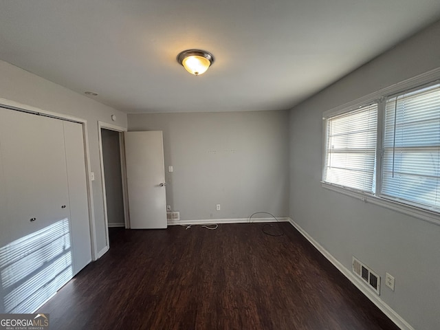 unfurnished bedroom featuring dark wood-type flooring and a closet