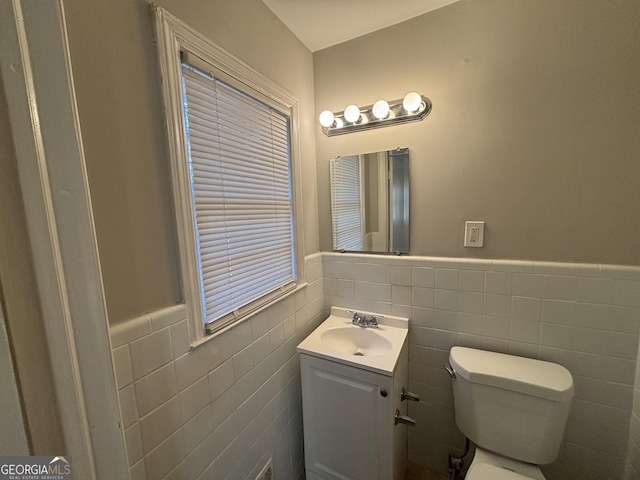 bathroom with tile walls, toilet, and vanity