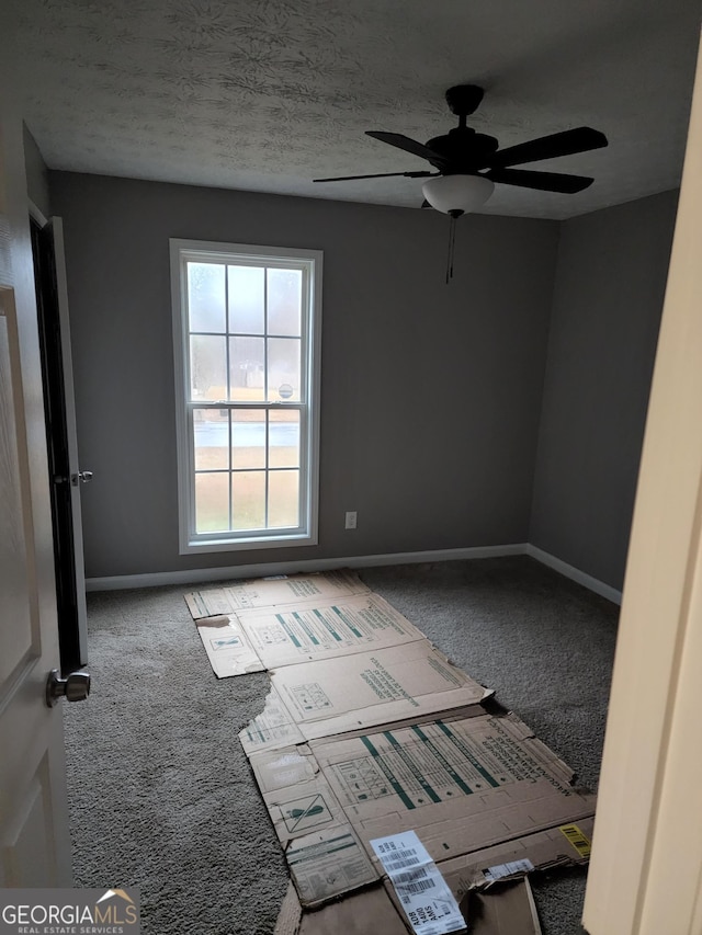 empty room featuring a textured ceiling, carpet floors, and ceiling fan