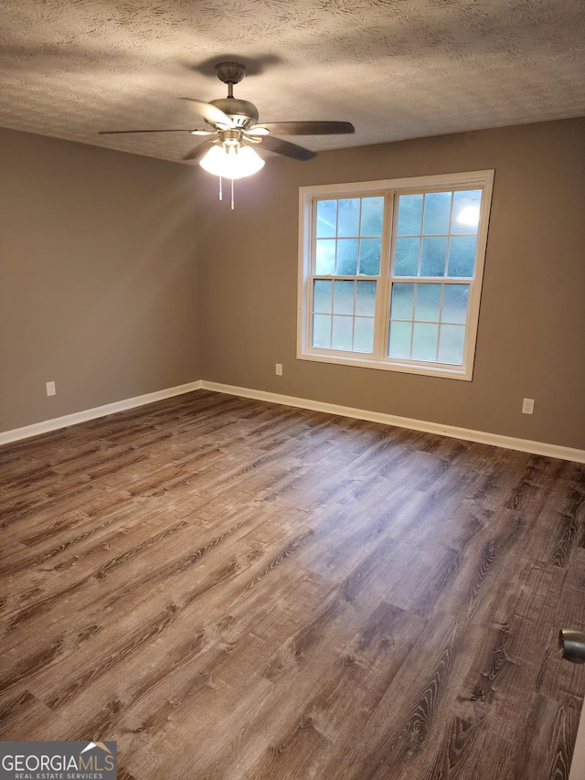 empty room with ceiling fan, wood-type flooring, and a textured ceiling