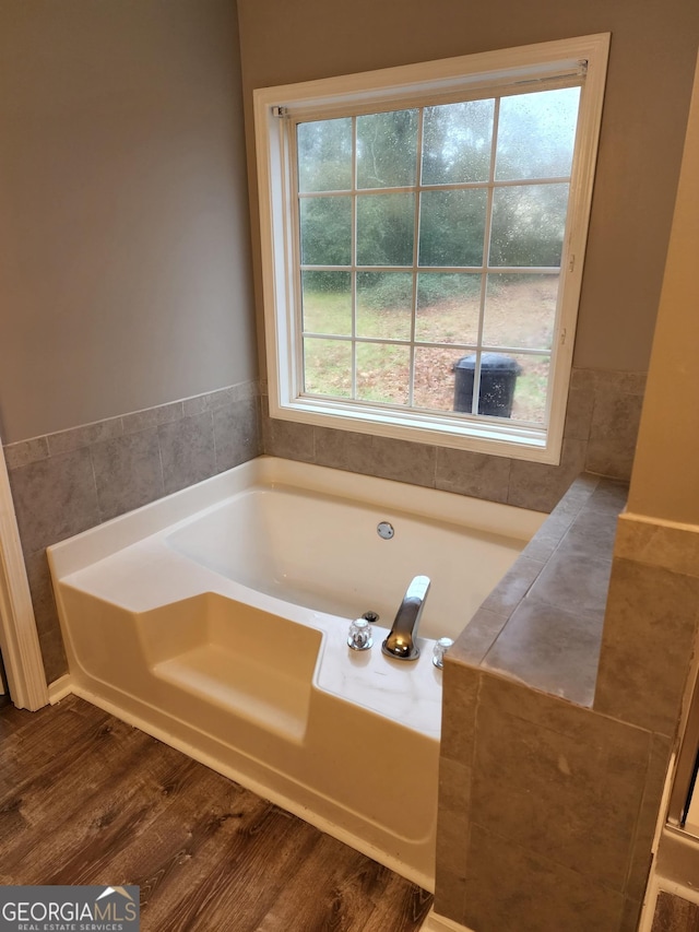 bathroom with wood-type flooring, a wealth of natural light, and tile walls