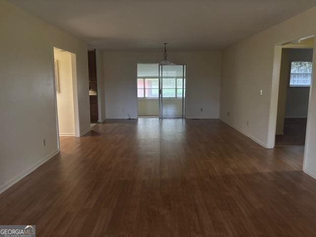 spare room with a wealth of natural light and dark wood-type flooring