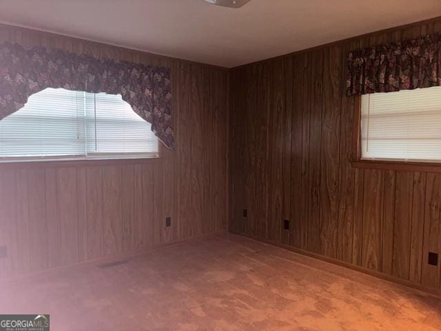 carpeted spare room featuring wood walls