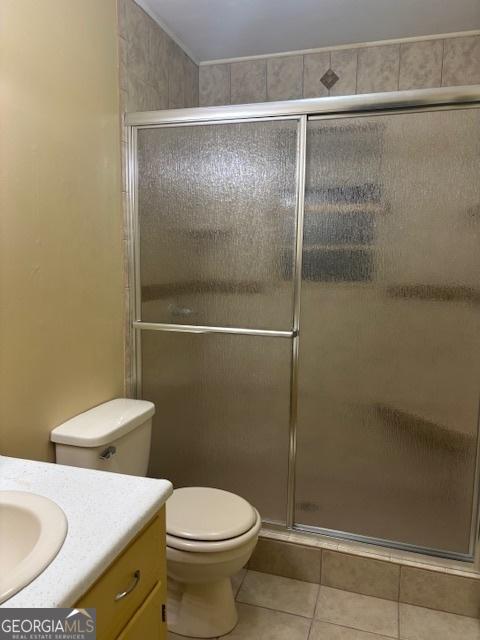 bathroom featuring tile patterned floors, vanity, a shower with shower door, and toilet