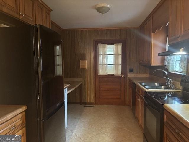 kitchen with ornamental molding, wooden walls, sink, exhaust hood, and black appliances