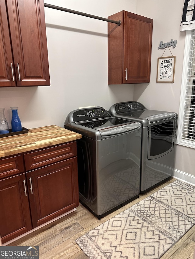 laundry area featuring independent washer and dryer, cabinets, and light wood-type flooring