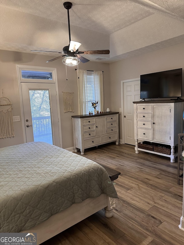 bedroom with multiple windows, dark hardwood / wood-style flooring, access to outside, and ceiling fan