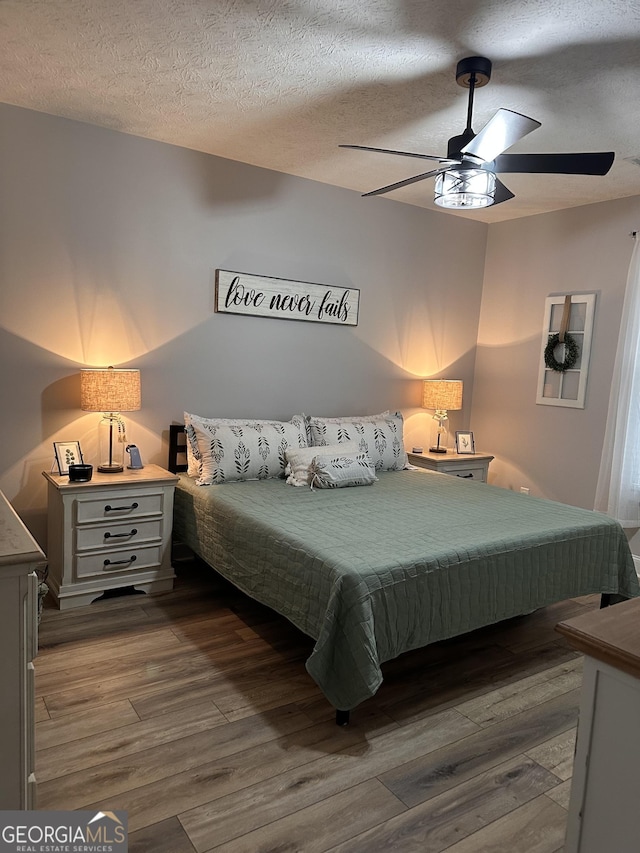 bedroom featuring ceiling fan, wood-type flooring, and a textured ceiling