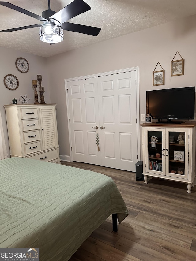 bedroom featuring a textured ceiling, ceiling fan, a closet, and dark hardwood / wood-style floors