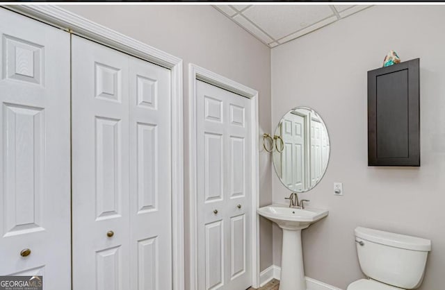 bathroom featuring toilet, a drop ceiling, and sink