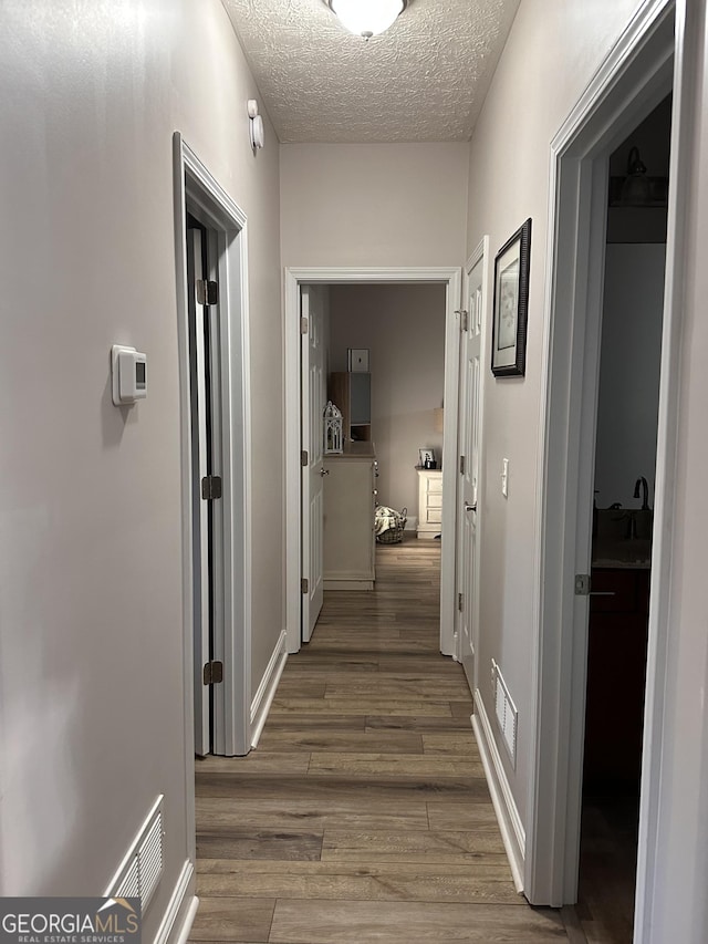 hallway featuring a textured ceiling and dark hardwood / wood-style flooring