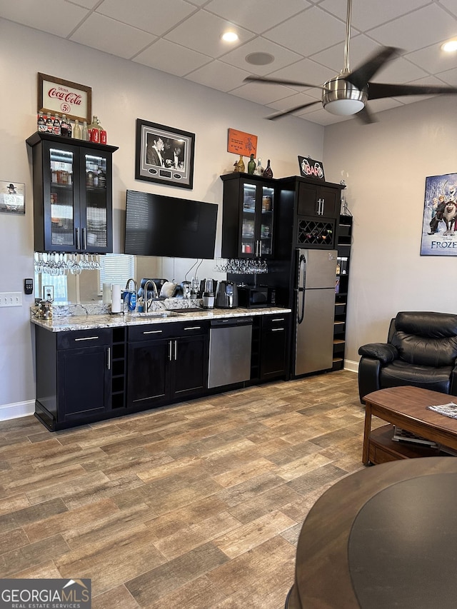 kitchen featuring sink, ceiling fan, light stone countertops, light wood-type flooring, and stainless steel appliances